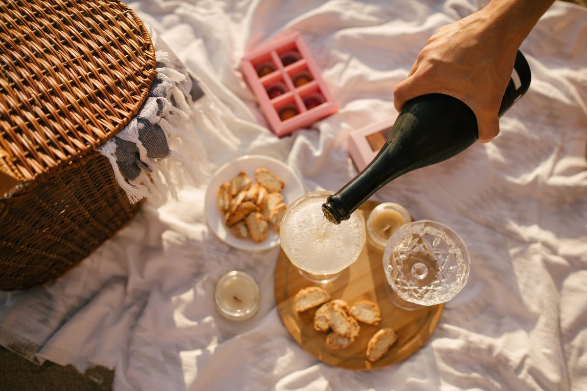 Beautiful summer picnic with champagne and sweets at sunset on the beach